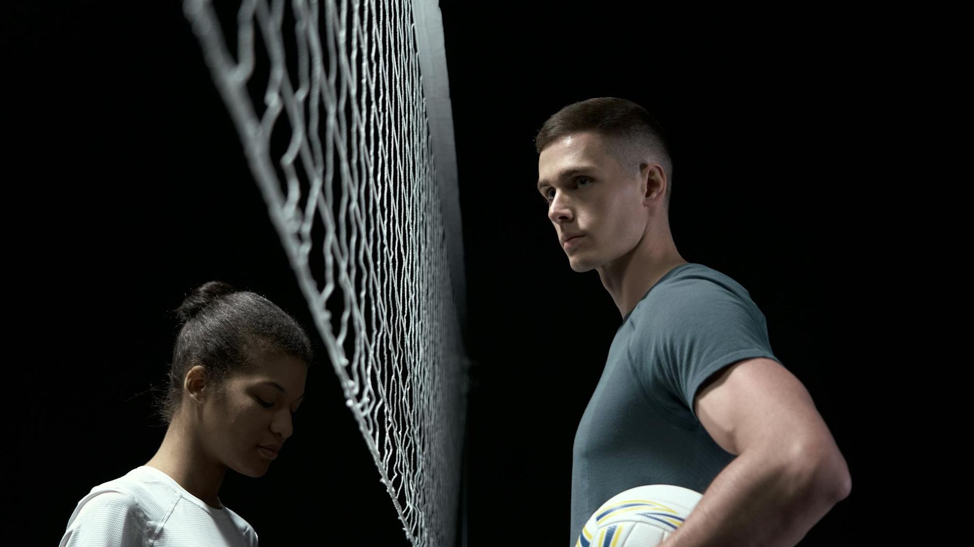 Athletic woman silhouette performing a strength exercise in a dark studio.